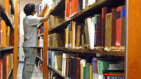 Young man looking for a book in a library
